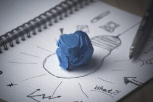 a crumpled blue paper in the center of a lightbulb drawn on paper 